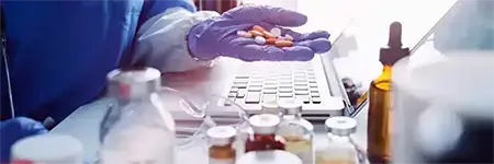 A lab worker surrounded by pills and medications.