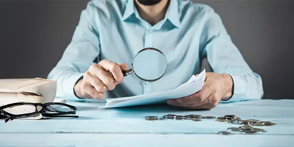 A project controller investigating hidden costs in a project with a magnifying glass