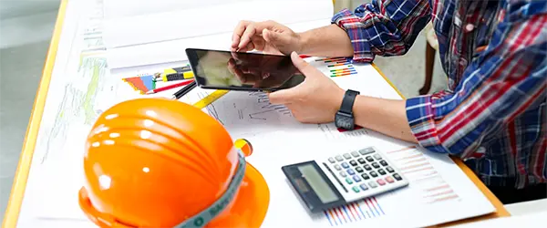 A professional using a tablet to manage the impact of inflation on construction project budgets